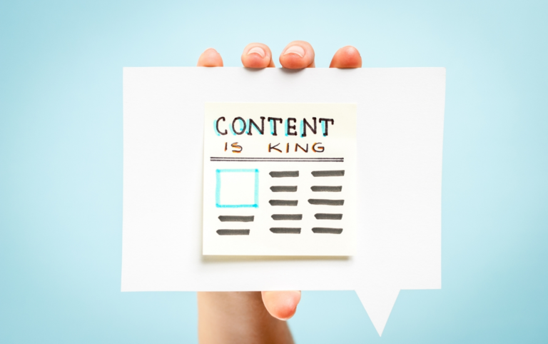 Hand holding a cardboard with the words "Content is King" pasted on it.